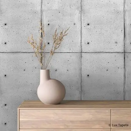 Samolepljiva tapeta betonske ploče sa ankerima na mat foliji iza komode od svetlog drveta sa keramičkom vazom