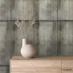 Samolepljiva tapeta stari beton sivo maslinasti na mat foliji iza komode od svetlog drveta sa keramičkom vazom