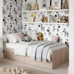 Twin wooden bed with built-in drawers, white and gray bedding, and plush toys against bold zebra-pattern wallpaper with shelves of books and decor above.