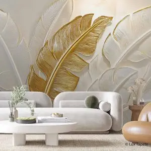 Living room with a large botanical wall mural of gold and white tropical leaves behind a white sofa.
