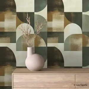 Powder-pink vase with dried stems on a light wooden dresser against a geometric patterned wallpaper.