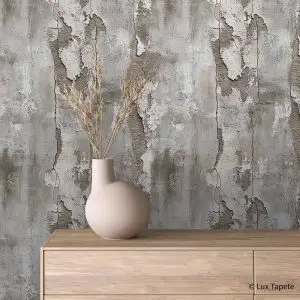 Beige rounded vase with dried stems on a light wood dresser against a distressed concrete wall.
