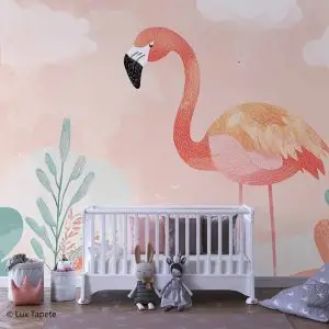 White baby crib in a pastel pink nursery with a large flamingo mural and plush rabbits nearby.
